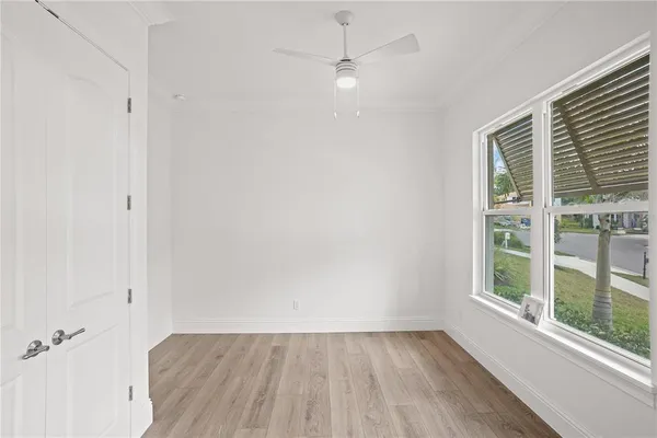 a view of an empty room with a window and wooden floor