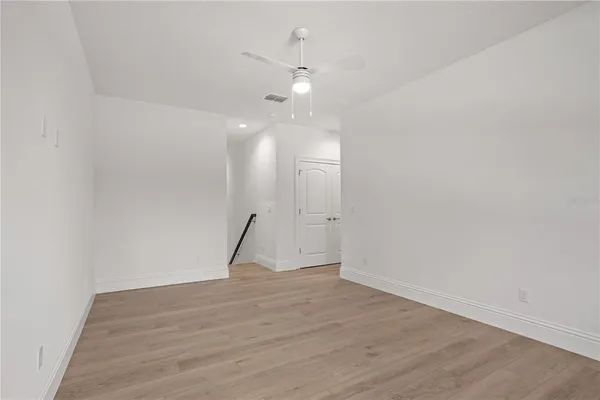 an empty room with wooden floor cabinet and a ceiling fan