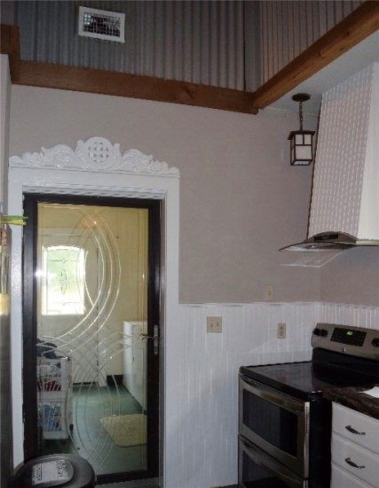 5325 County Road 2291 Centerville, TX 75833 - Photo 21 of 31 Kitchen featuring stainless steel range with electric cooktop, wainscoting, range hood, white cabinetry, and dark countertops