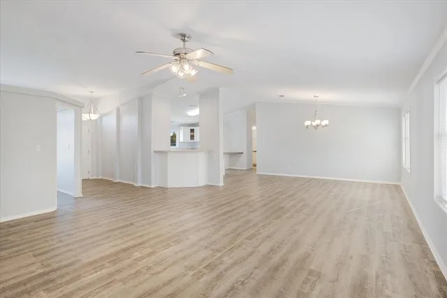 a view of an empty room with wooden floor and a kitchen