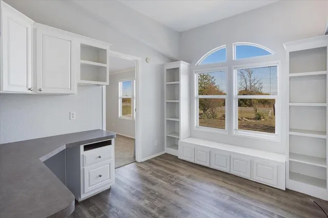 a view of an empty room with a window and wooden floor