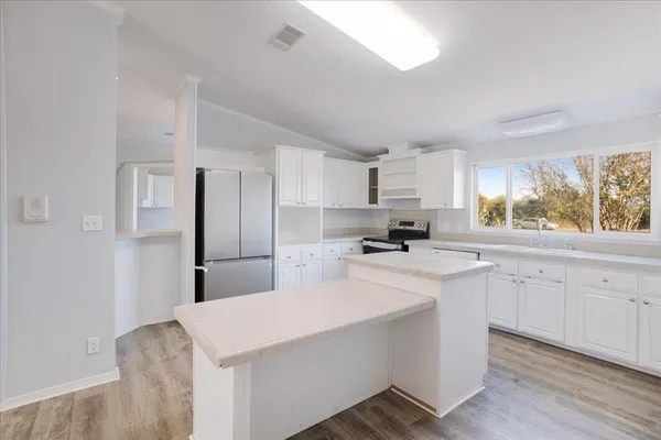 a kitchen with stainless steel appliances a sink a stove a refrigerator cabinets and a window