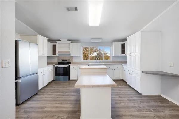 a kitchen with granite countertop a refrigerator stove top oven and sink