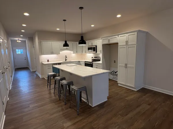 a open kitchen with stainless steel appliances granite countertop a table chairs refrigerator and microwave