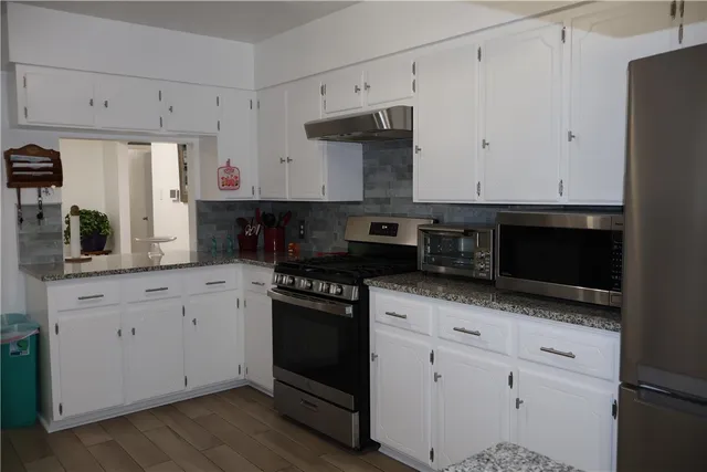 a kitchen with granite countertop white cabinets and black appliances