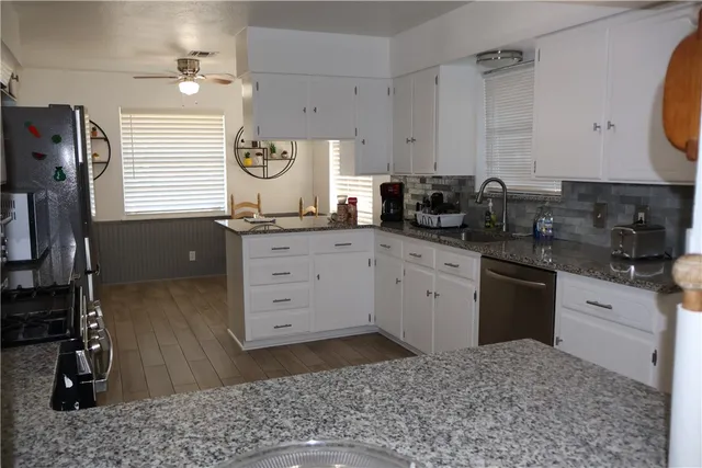 a kitchen with granite countertop a sink a stove and cabinets