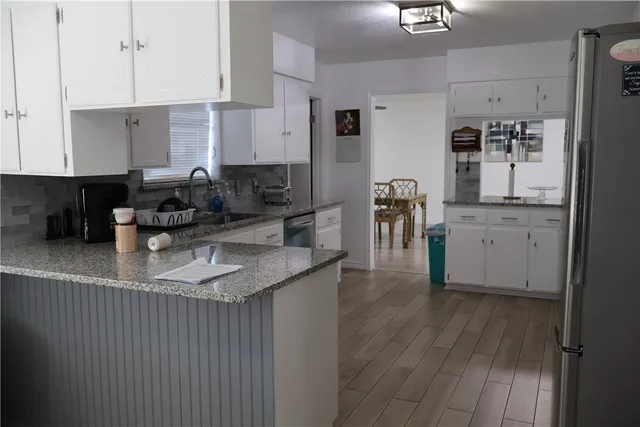 a kitchen with kitchen island granite countertop a sink cabinets and wooden floor