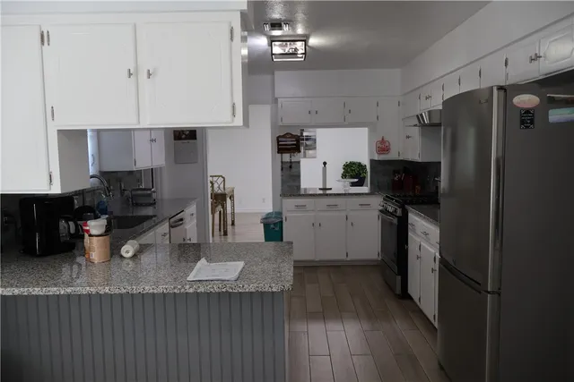 a kitchen with stainless steel appliances granite countertop a sink refrigerator and cabinets