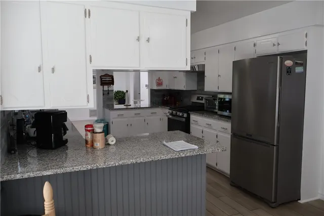 a kitchen with granite countertop a refrigerator a stove a sink a counter space and cabinets