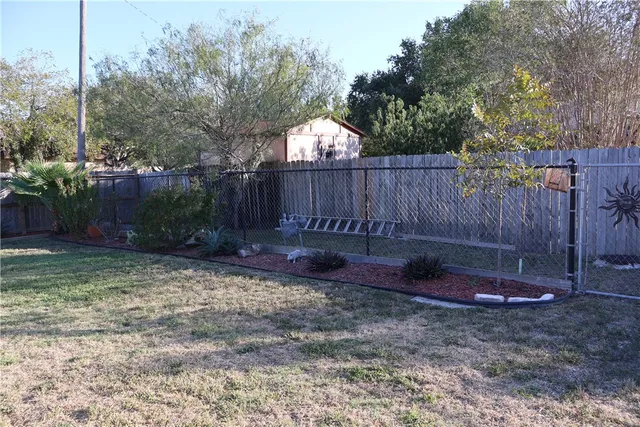 a view of a backyard with large trees and wooden fence