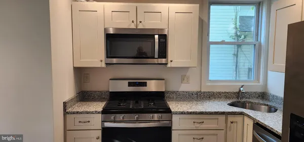 a kitchen with granite countertop a stove sink and microwave