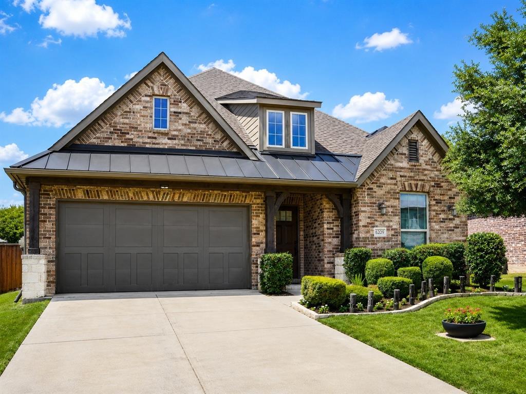 6209 Cupleaf Road Flower Mound, TX 76226 - Photo 2 of 29 Brick and stone facade featuring a prominent two-car garage, dormer window, covered entry, and structured landscaping