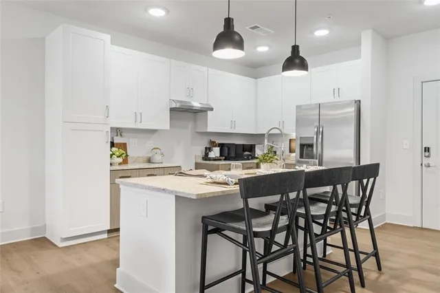 a kitchen with stainless steel appliances kitchen island granite countertop a dining table chairs and white cabinets