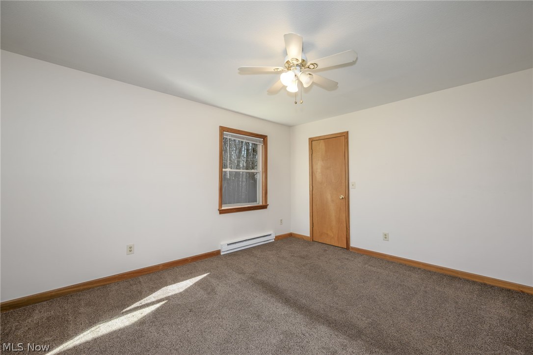 8464-8446 Tallmadge Road Diamond, OH 44412 - Photo 19 of 39 Carpeted spare room featuring a baseboard heating unit and ceiling fan