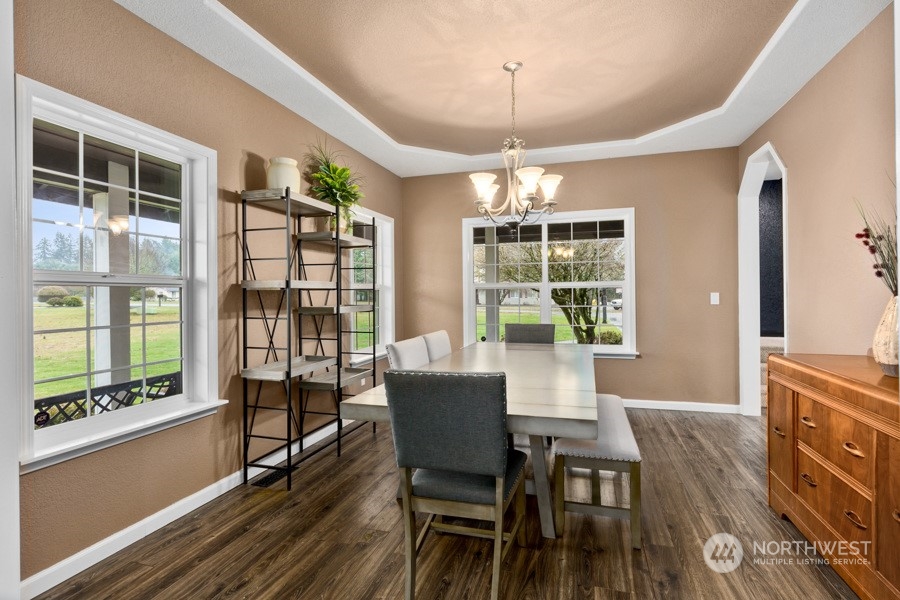 9600 Gastaeson Lane Southwest Rochester, WA 98579 - Photo 9 of 39 a dining room with wooden floor a chandelier a wooden table and chairs