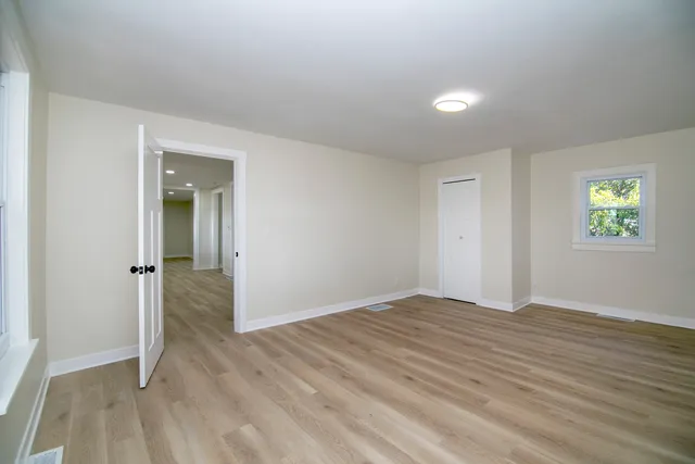 a view of empty room with wooden floor and fan