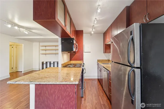a kitchen with refrigerator and wooden floor