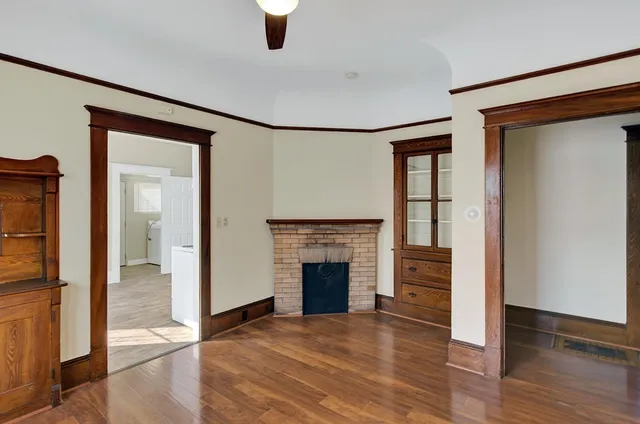 an empty room with wooden floor fireplace and windows