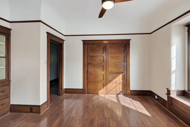 a view of empty room with wooden floor and fan