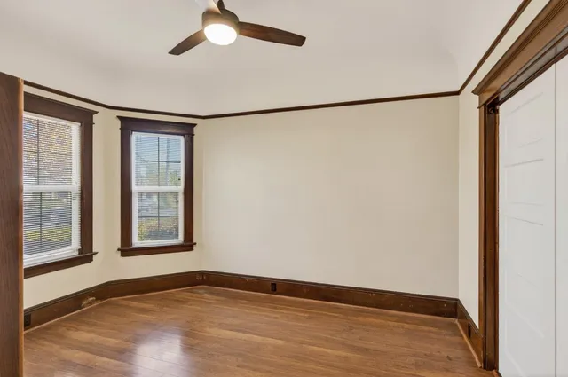 a view of an empty room with a window and wooden floor