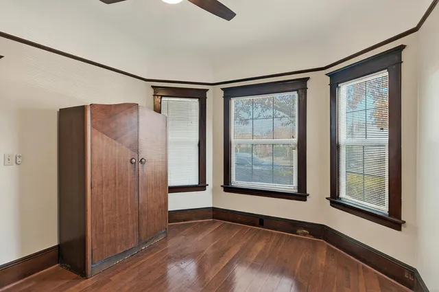 a view of an empty room with a window and wooden floor