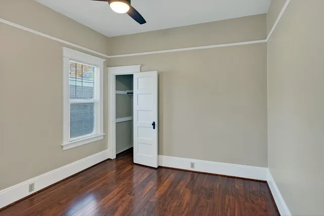 an empty room with wooden floor cabinet and windows