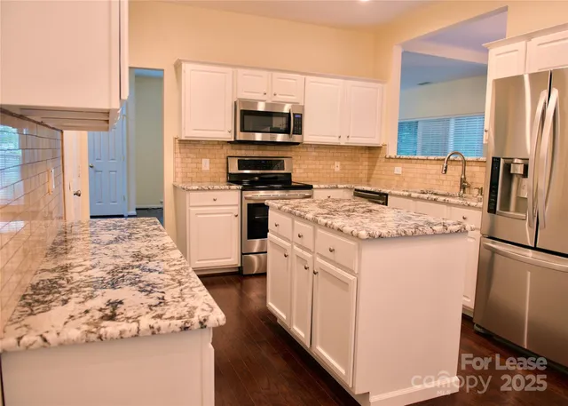 a kitchen with white cabinets and stainless steel appliances