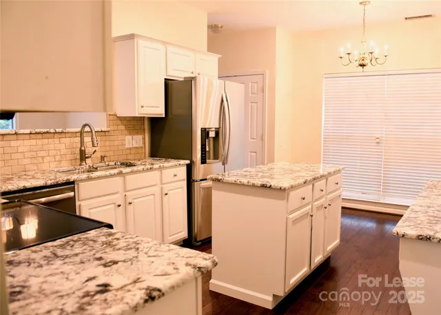 a kitchen with stainless steel appliances kitchen island granite countertop a sink stove and refrigerator