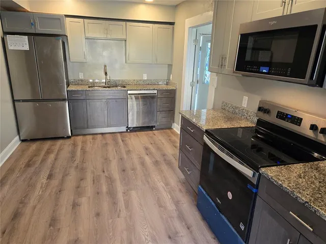 a kitchen with stainless steel appliances granite countertop a stove a sink and a microwave