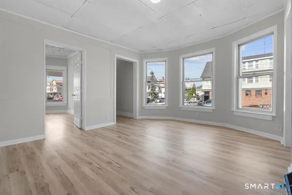 a view of an empty room with window and wooden floor