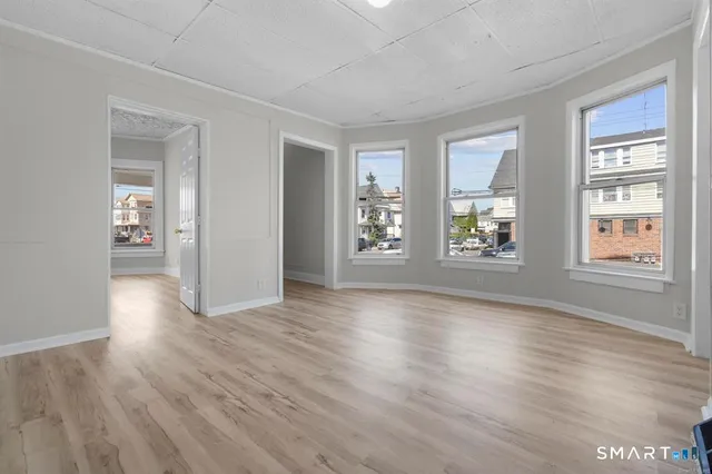 a view of an empty room with window and wooden floor