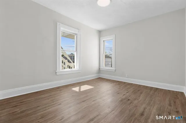 a view of an empty room with wooden floor and a window