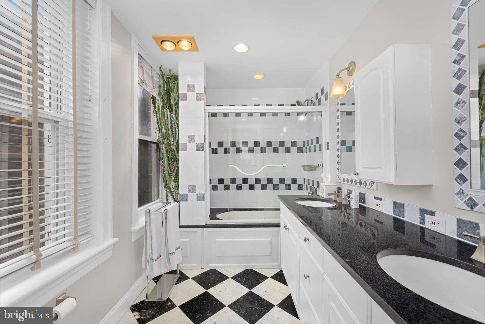 1855 Calvert Street Northwest, Unit 203 Washington, DC 20009 - Photo 7 of 9 a bathroom with a granite countertop double vanity sink a mirror a bathtub and next to a window