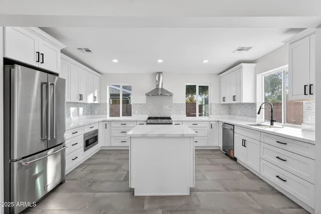 a large kitchen with stainless steel appliances granite countertop a stove oven and a refrigerator