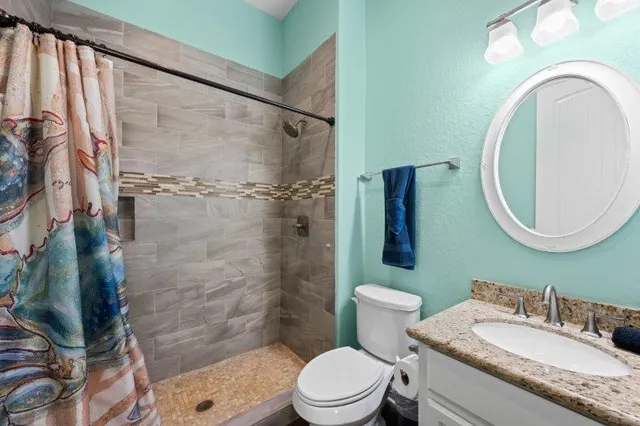 a bathroom with a granite countertop sink mirror toilet and shower