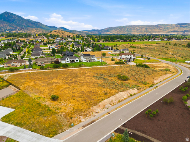 574 South Fox Den Road, Unit 3 Midway, UT 84049 - Photo 37 of 45 Expansive undeveloped lot presenting clear ground, paved road frontage, and established residential structures in the background