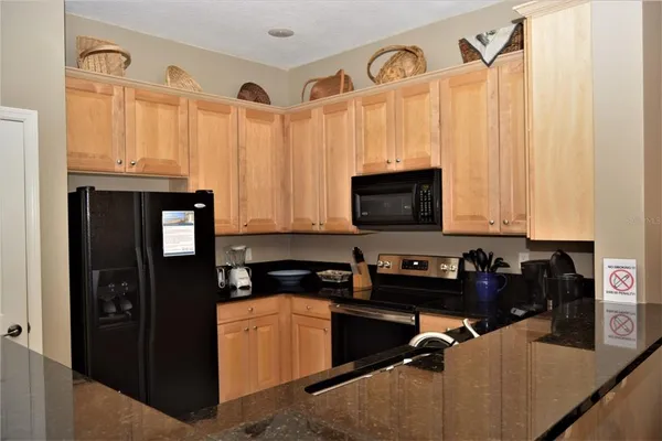 a kitchen with granite countertop a refrigerator a stove a microwave oven cabinets and a counter top space