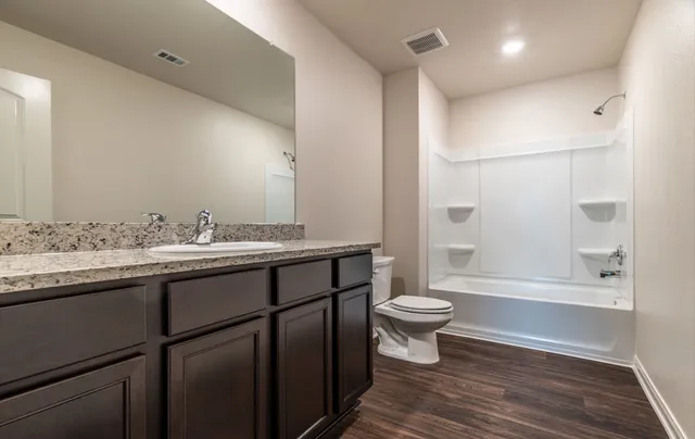 a bathroom with a sink a toilet a mirror and shower