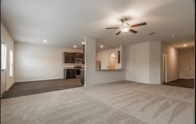 a view of an empty room with a ceiling fan and window