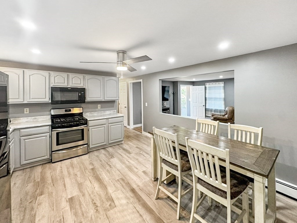 3 Maple Ridge Road, Unit 3 Seabrook, NH 03874 - Photo 5 of 26 a kitchen with granite countertop a stove top oven a sink dishwasher a dining table and chairs with wooden floor