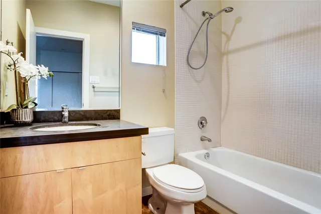 a bathroom with a granite countertop sink a toilet and bathtub