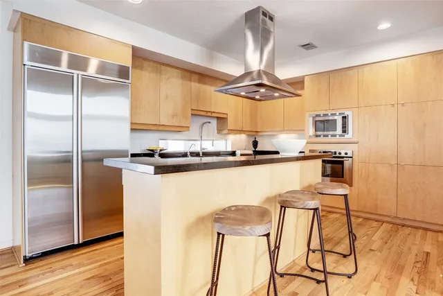 a kitchen with a refrigerator a stove a sink and a dining table with wooden floor