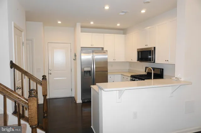 a kitchen with stainless steel appliances granite countertop a refrigerator a stove a sink and a microwave