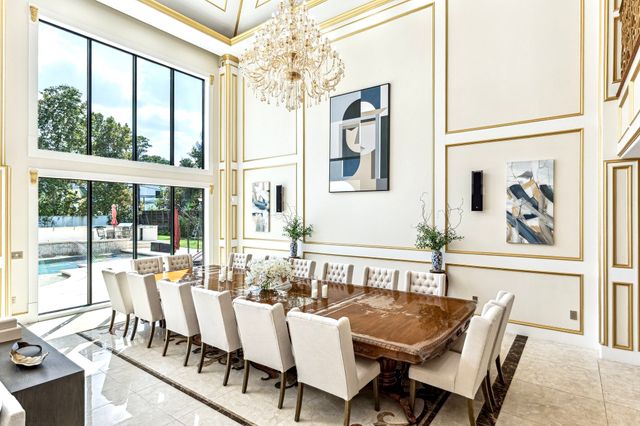 a view of a dining room with furniture a chandelier and large windows