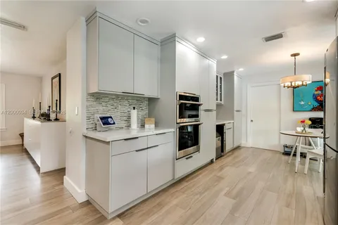 a kitchen with stainless steel appliances a refrigerator a sink a stove and chairs with wooden floor