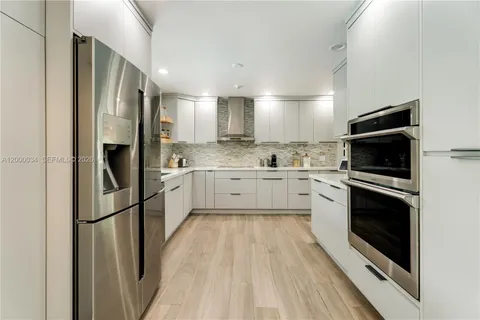 a kitchen with granite countertop white cabinets white appliances a sink and a large window