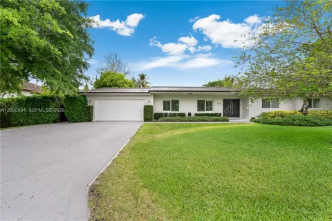a view of a house with a big yard and palm trees