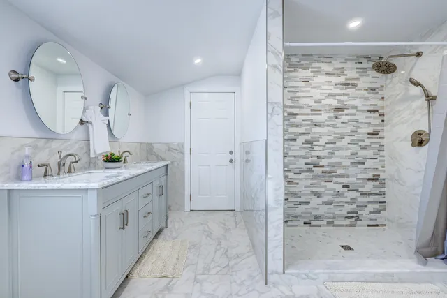 a bathroom with a double vanity sink mirror and shower