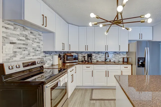 a kitchen with stainless steel appliances granite countertop a stove sink and cabinets