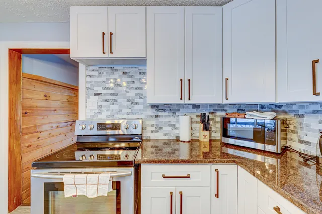 a kitchen with stainless steel appliances granite countertop a stove and a white cabinets